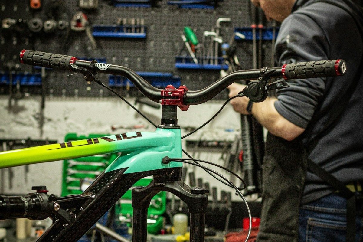 A green full-suspension mountain bike held in a workshop repair stand