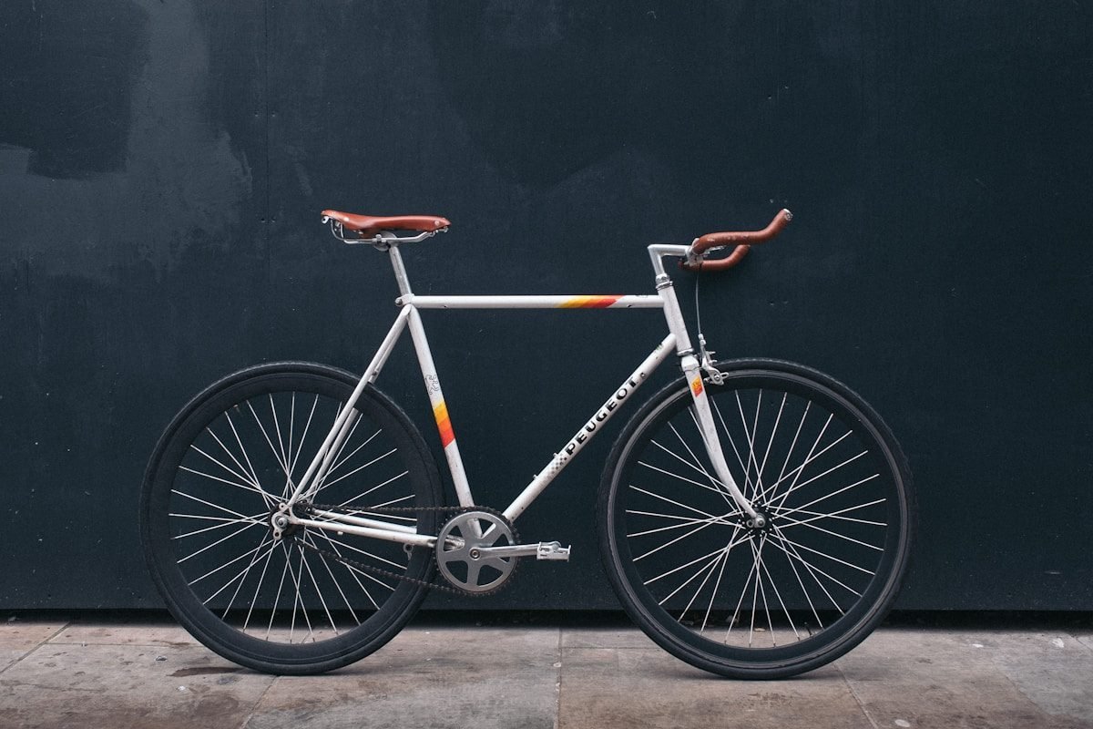 A silver steel road bike with brown leather saddle, side-on against a dark background