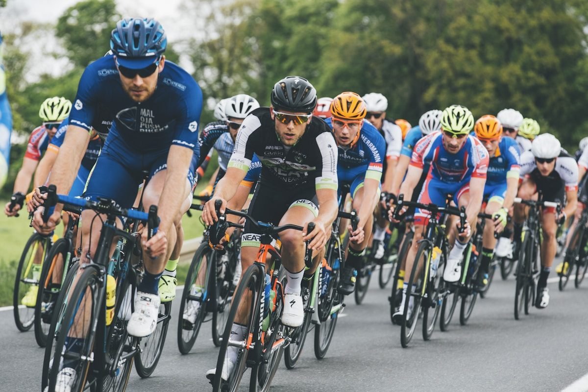 A tightly packed group of road cyclists in coloured jerseys riding together