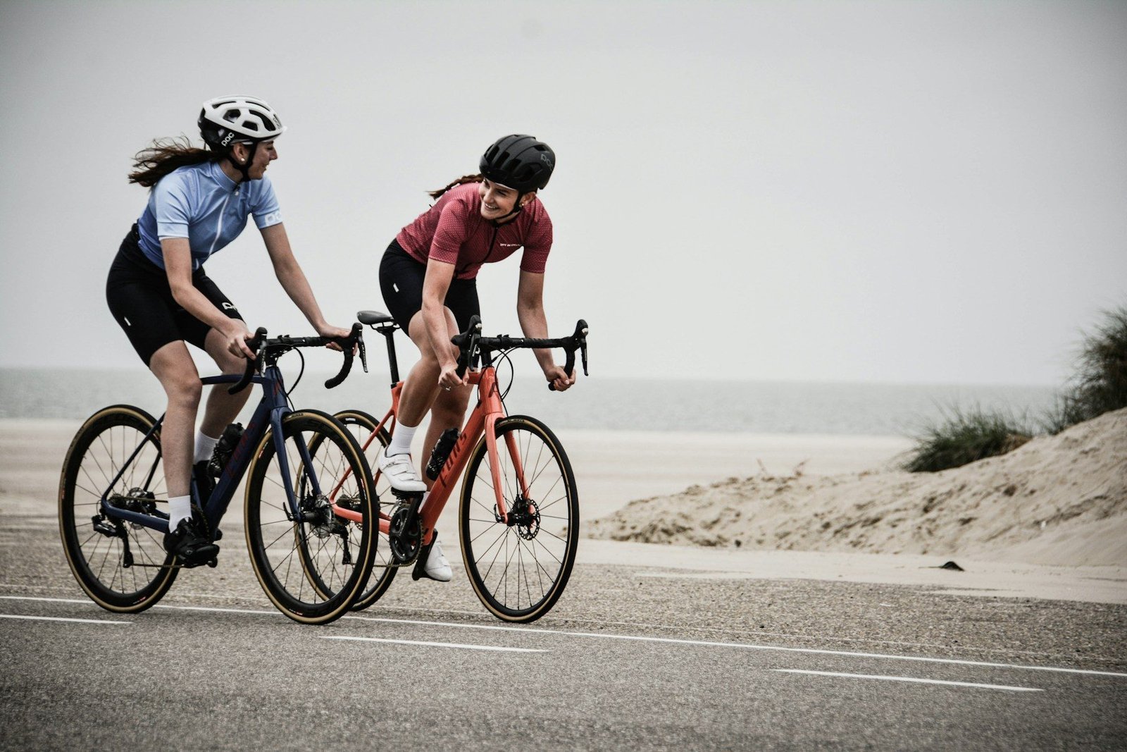 Two cyclists riding side by side along an open coastal road