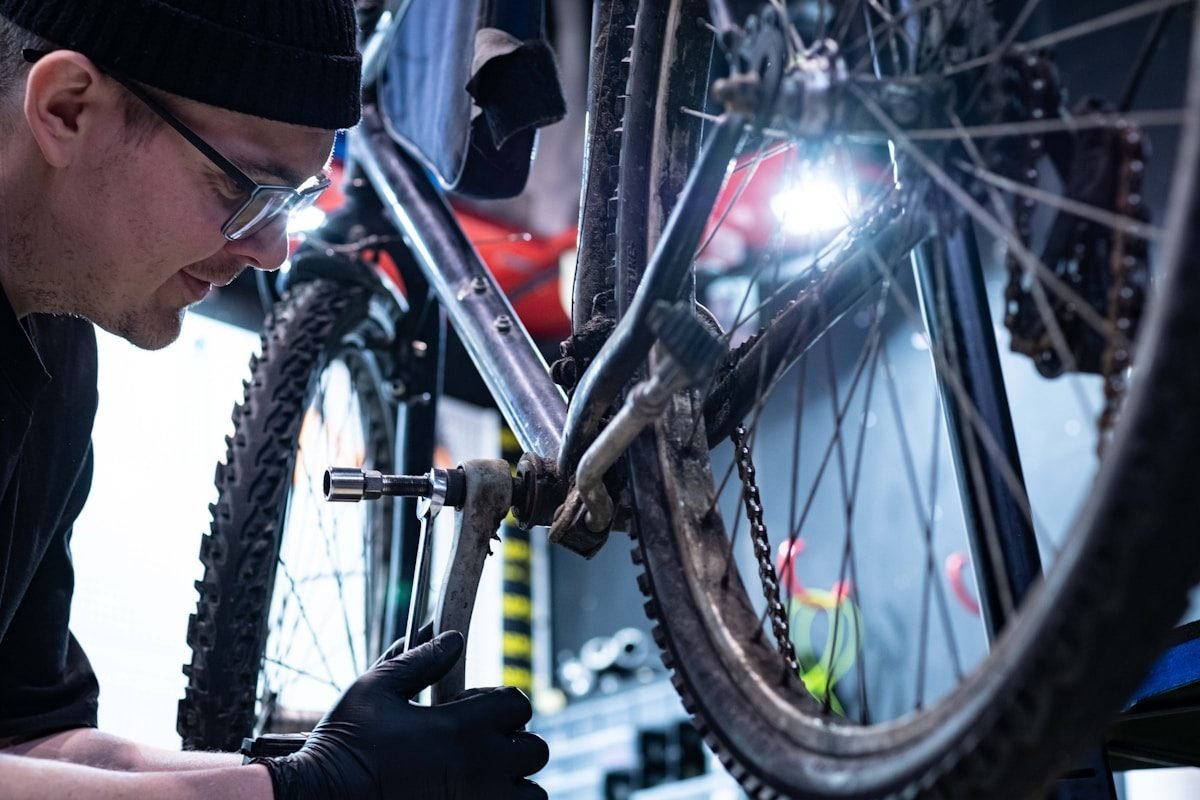 A mechanic wearing a head torch adjusting the rear derailleur of a bicycle