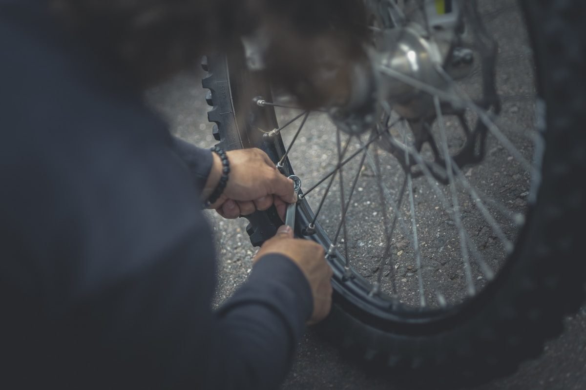 Close-up of hands fitting a tyre back onto a bicycle wheel rim
